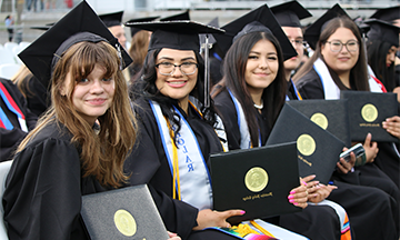Four graduates holding degrees